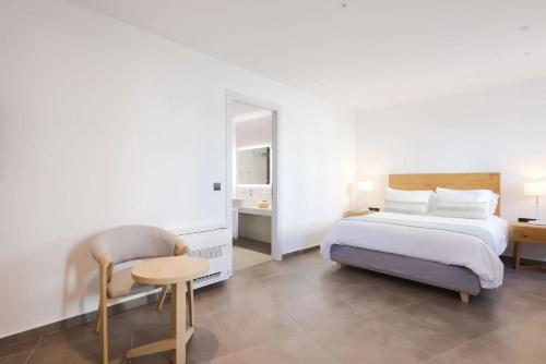 a bedroom with a bed and a table and a chair at Aeifos Boutique Hotel in Imerovigli
