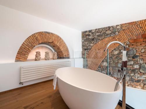 una vasca bianca in un bagno con parete di mattoni di Casa Giorgio Luxury apartment with Stunning View a Menaggio