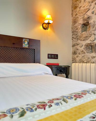 a bedroom with a white bed and a stone wall at La Posada del Rey in Llanes