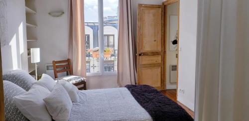 une chambre avec un lit et une grande fenêtre dans l'établissement Appartement avec balcon au cœur PARIS, à Paris