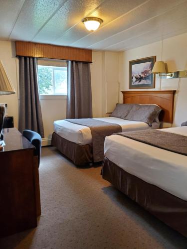 a hotel room with two beds and a desk at Alaska Country Inn in Delta Junction