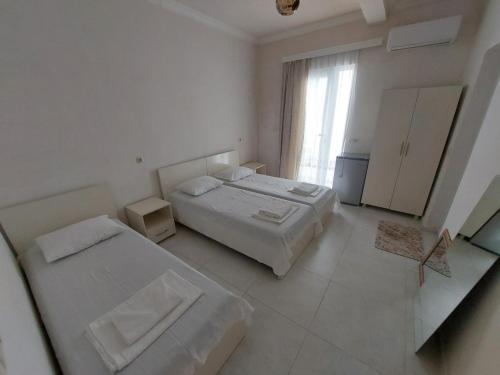 a white room with two beds and a window at Hotel NUCA in Gonio