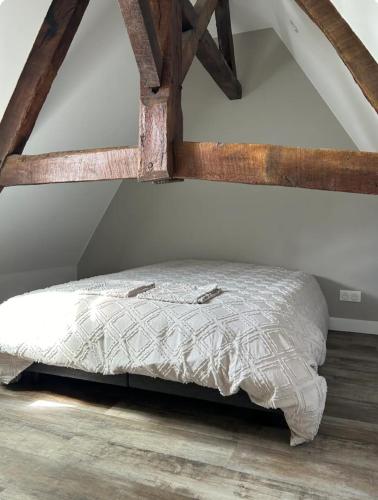 Ce lit se trouve dans un dortoir doté de poutres apparentes. dans l'établissement Appartement en duplex Trevieres 3 eme étage, à Trévières