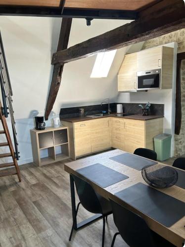 une cuisine avec une table et des chaises dans une pièce dans l'établissement Appartement en duplex Trevieres 3 eme étage, à Trévières