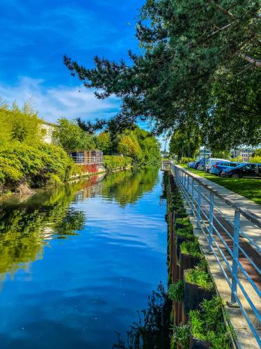 a river with blue water and trees on the side at Pénélope by Kleidos - Charmant Studio Centre Pont-Audemer in Pont-Audemer