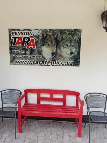 a red bench against a wall with a picture of wolves at pension TARA in Teplice nad Metují