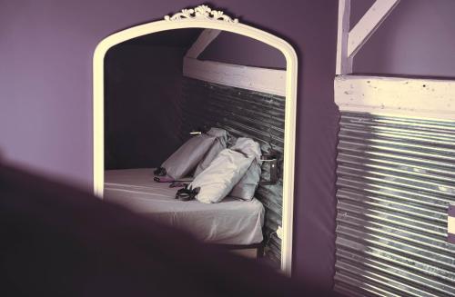a mirror reflecting a bed in a purple room at Bisous Bisous - Romantique Room in Riom