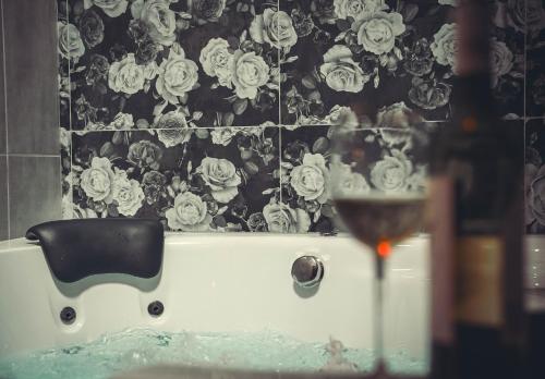 a bath tub with a glass of wine in a bathroom at Bisous Bisous - Romantique Room in Riom
