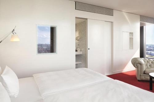 a white bedroom with a bed and a chair at Empire Riverside Hotel in Hamburg