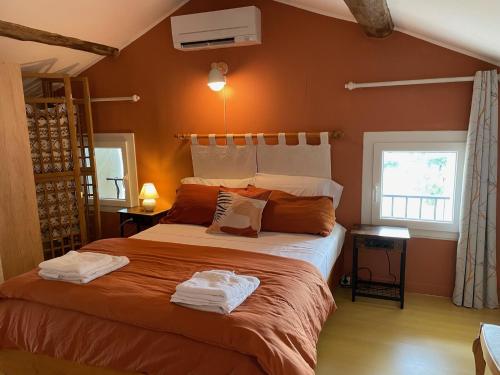 une chambre avec un grand lit aux murs orange dans l'établissement Le Mas g'Ardéchois, à Saint-Paul-le-Jeune