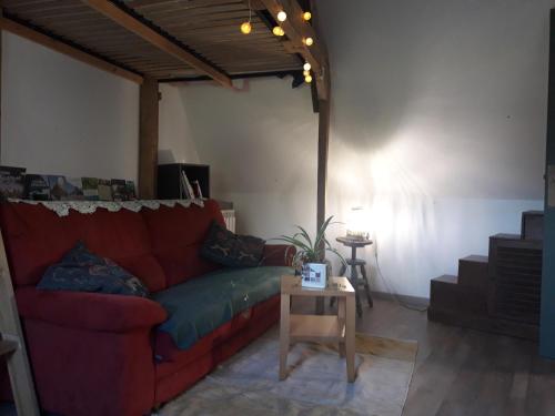 un salon avec un canapé rouge et une table dans l'établissement Chambre chez l'habitant a la campagne, à Bazouges-la-Pérouse
