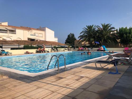 une grande piscine avec des gens dans l'eau dans l'établissement Votre espace glamour EN COHABITATION avec nous deux dans notre appartement du village naturiste, au Cap d'Agde