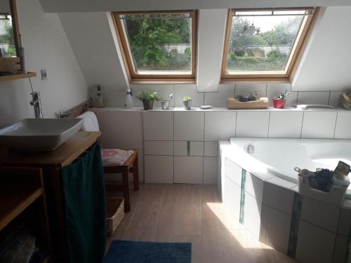 La salle de bains est pourvue d'une baignoire, d'un lavabo et de 2 fenêtres. dans l'établissement Chambre chez l'habitant a la campagne, à Bazouges-la-Pérouse