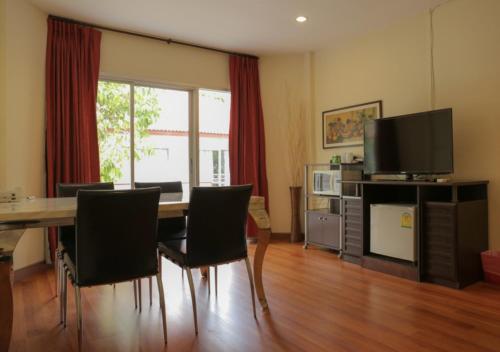 a living room with a table with chairs and a television at Kiatthada Resort in Bangkok