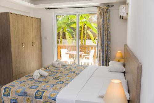 a bedroom with a bed and a balcony at Alecos Hotel Apartments in Paphos