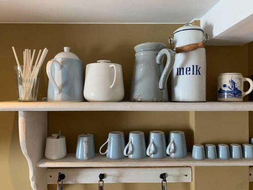 a shelf filled with blue and white cups and utensils at Smederij Abbekerk, guesthouse in Abbekerk