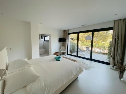 une chambre avec un lit blanc et une grande fenêtre dans l'établissement Villa Fontvieille, à Zonza