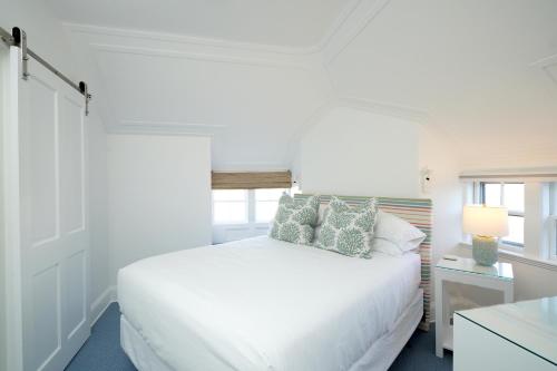a white bedroom with a white bed and a window at 76 Main Ink Press Hotel in Nantucket