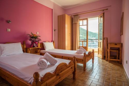 Duas camas num quarto com paredes cor-de-rosa em Sivota Bay em Sivota