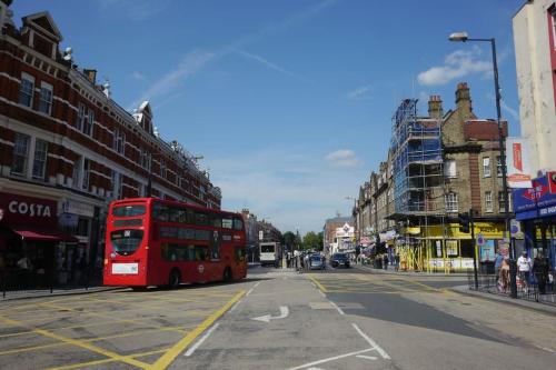 a red double decker bus driving down a city street at 37chats studio in London