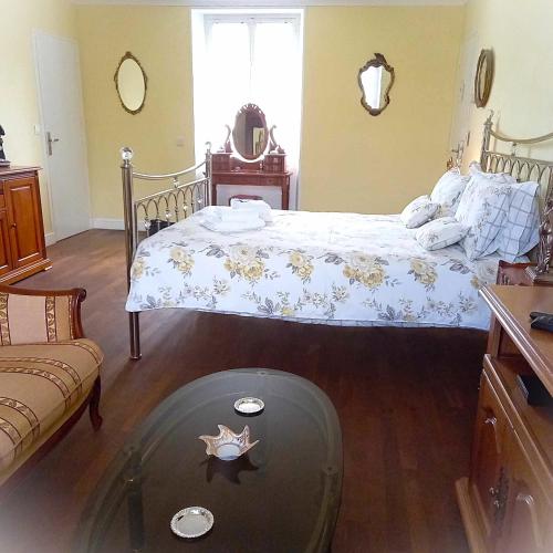 a bedroom with a bed and a glass table at Le Potier Jovial in Ger