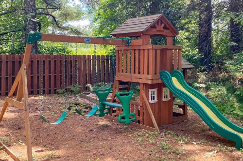 a wooden playset with a slide and a playground at Hidden River Lodge in Eagle River