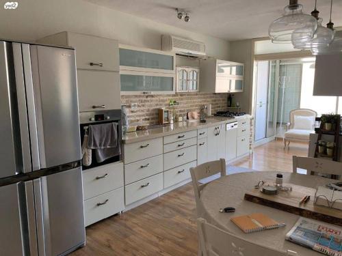 a kitchen with a stainless steel refrigerator and a table at דירה מהממת ברמת גן in Ramat Gan
