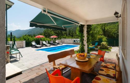 Un patio con mesa y sillas y una piscina. en Holiday Home Podaspilje I, en Svinišće