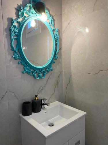 a bathroom with a white sink and a blue mirror at Yaya house in Skala Sotiros