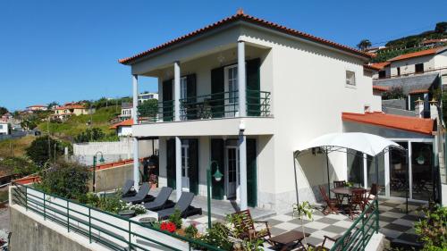 a white house with chairs and tables on a balcony at Jango Paradise in Funchal