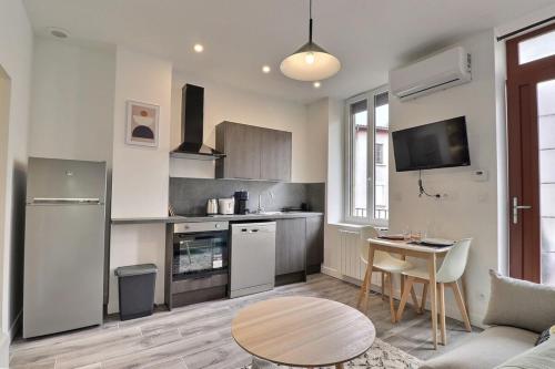 une cuisine et un salon avec un canapé et une table dans l'établissement Le Péri - T1 Apartment 4 Guests - Villeurbanne, à Villeurbanne