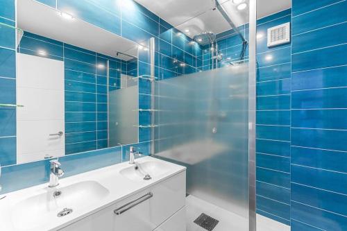 W wyłożonej niebieskimi kafelkami łazience znajduje się umywalka i lustro. w obiekcie Edificio Miami, 2 bedroom w mieście Nerja