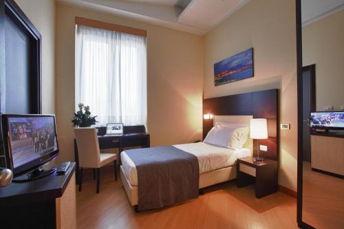 a hotel room with a bed and a desk and a television at Hotel Naples in Naples