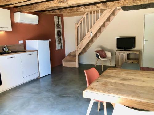 a kitchen and dining room with a table and a staircase at La Jasse in Saint-Beauzély