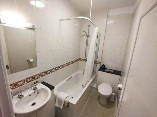 a bathroom with a sink and a tub and a toilet at Chough's Nest Hotel in Lynton