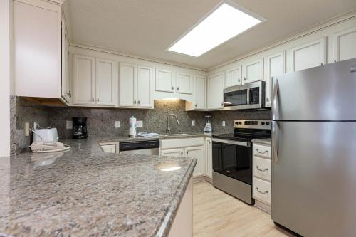 a kitchen with white cabinets and a stainless steel refrigerator at Phoenix X 212 condo in Orange Beach