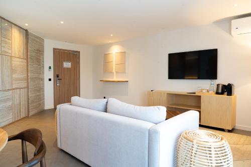 a living room with a white couch and a tv at AP Cabanas Beach & Nature - Adults Friendly in Cabanas de Tavira