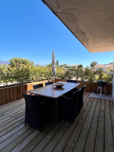 a wooden deck with a table and chairs on it at Résidence Storia di Blue in Porto-Vecchio
