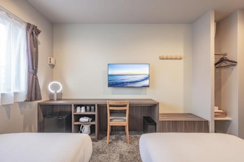 a bedroom with two beds and a desk with a tv at Elite Inn Kyoto Station エリートイン京都駅 in Kyoto