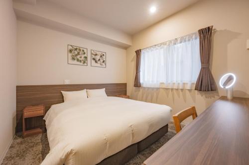 a bedroom with a bed and a table and a window at Elite Inn Kyoto Station エリートイン京都駅 in Kyoto