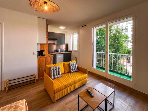 un salon avec un canapé jaune et une cuisine dans l'établissement Appartement cosy Paris, à Bagnolet