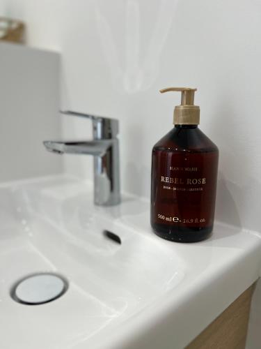 une bouteille de savon posée sur un lavabo de salle de bain dans l'établissement Appartement cosy Paris, à Bagnolet