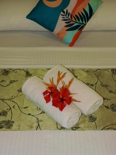 a towel with a flower on it on a bed at Chekesh Casa in Siquijor