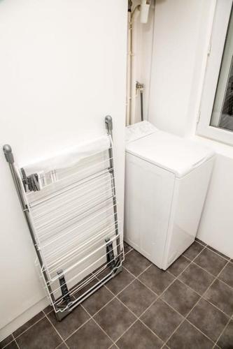 une buanderie avec un réfrigérateur blanc et un sol carrelé dans l'établissement Studio proche de Paris et Orly, à Alfortville