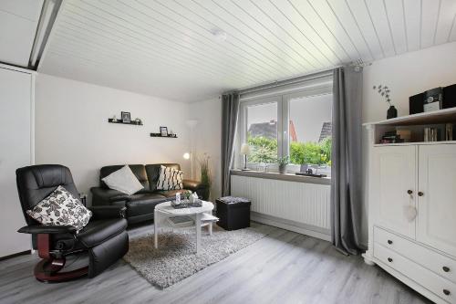 a living room with a black leather chair and a window at Nordsee-Ferienwohnung Halligland in Bredstedt