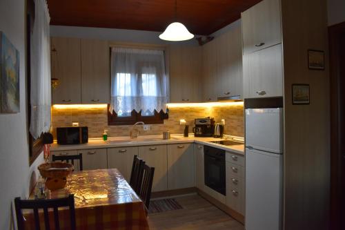a kitchen with white cabinets and a sink and a table at Konaki Guesthouse in Ormos Panagias