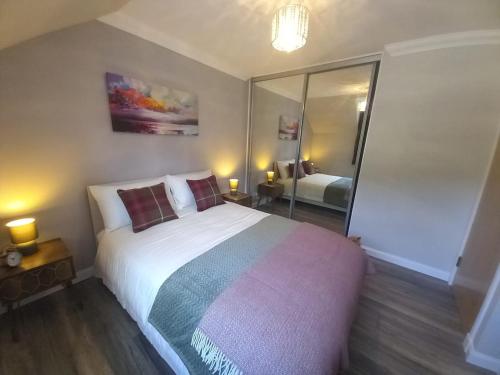 a bedroom with a large bed and a mirror at Idyllic Waterside Penthouse in Callander