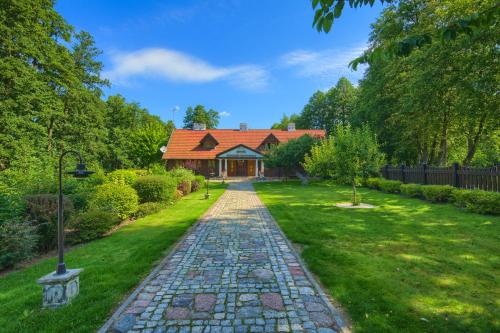 a house with a stone path in front of a yard at Hotel Dworek Wapionka in Górzno