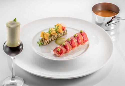 a white plate with sushi and a glass of wine at La Réserve de Beaulieu in Beaulieu-sur-Mer