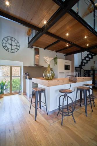une cuisine avec un comptoir et des tabourets dans une pièce dans l'établissement Corps de Ferme Idyllique en Bord de Rance, à Pleudihen-sur-Rance